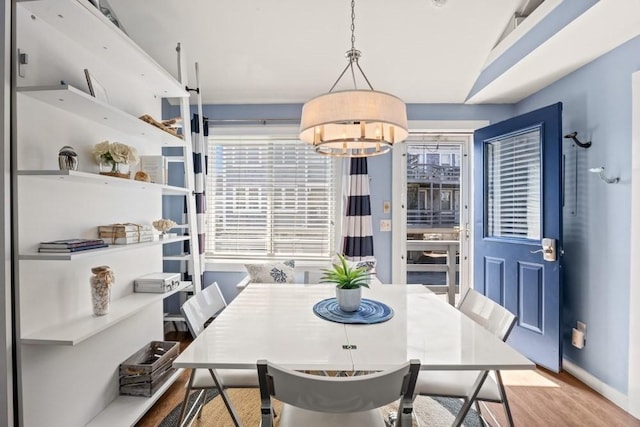 dining area featuring baseboards, wood finished floors, and a notable chandelier