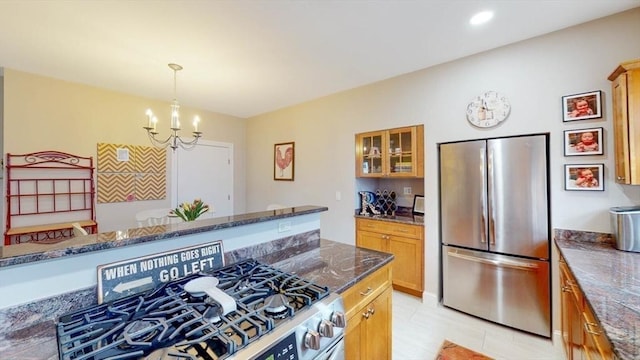 kitchen featuring appliances with stainless steel finishes, a chandelier, glass insert cabinets, pendant lighting, and dark stone countertops