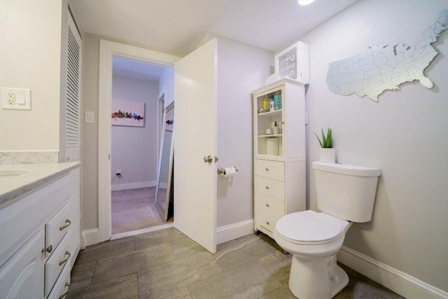bathroom featuring vanity, toilet, and baseboards
