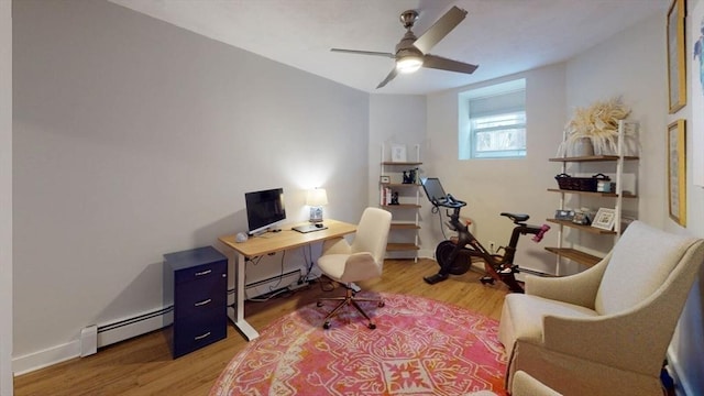 office area with a baseboard radiator, light wood finished floors, a ceiling fan, and baseboards