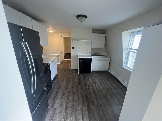 kitchen with black fridge with ice dispenser, baseboard heating, dark wood-type flooring, sink, and white cabinets