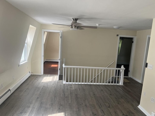 spare room with ceiling fan, dark wood-type flooring, and a baseboard heating unit