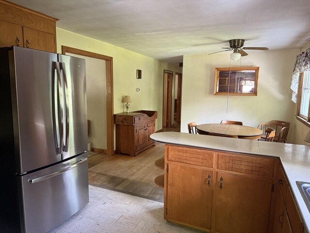 4 King Ln, Monson, MA 01057 - kitchen with freestanding refrigerator, light countertops, light wood-style flooring, brown cabinets, and a ceiling fan