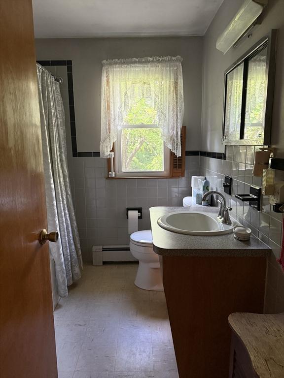 4 King Ln, Monson, MA 01057 - bathroom with a baseboard radiator, tile walls, vanity, toilet, and wainscoting