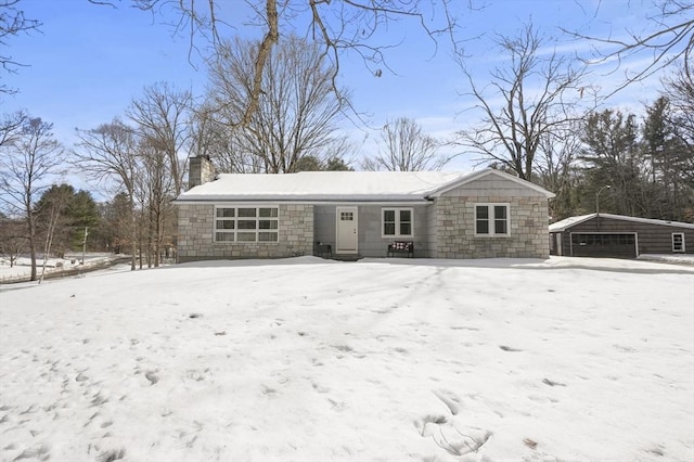 view of front of property with an outbuilding, stone siding, a chimney, and a detached garage