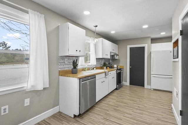 kitchen featuring stainless steel appliances, tasteful backsplash, white cabinetry, a sink, and extractor fan