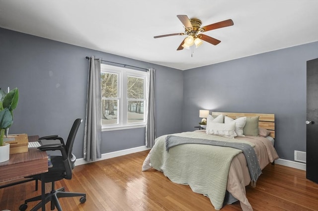 bedroom featuring a ceiling fan, visible vents, baseboards, and wood finished floors