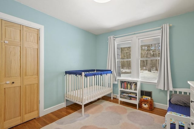 bedroom featuring a crib, baseboards, and wood finished floors