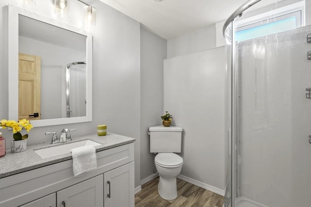 full bathroom featuring toilet, vanity, a shower stall, wood finished floors, and baseboards