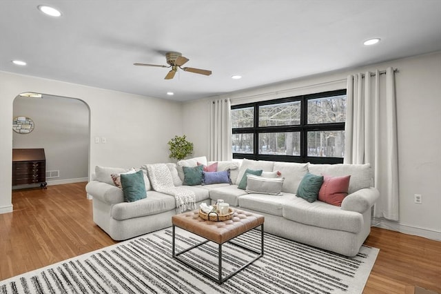 living area with visible vents, arched walkways, wood finished floors, and recessed lighting