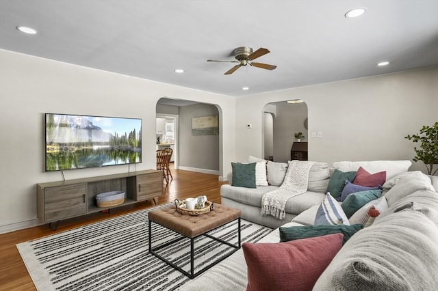 living room with arched walkways, baseboards, recessed lighting, and wood finished floors