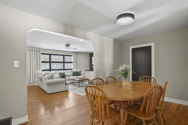 dining area featuring arched walkways, visible vents, ceiling fan, wood finished floors, and baseboards