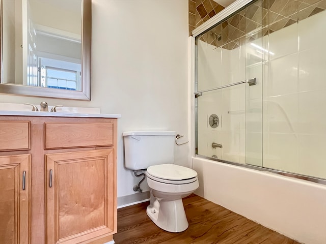 full bathroom with bath / shower combo with glass door, vanity, wood-type flooring, and toilet