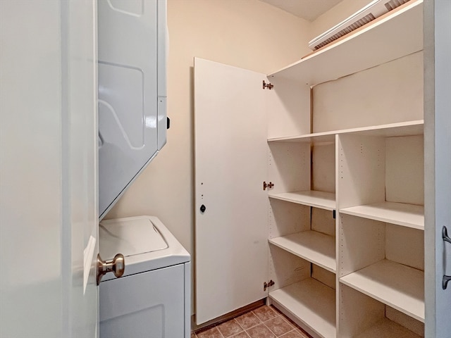 laundry area featuring light tile patterned floors and stacked washer / dryer