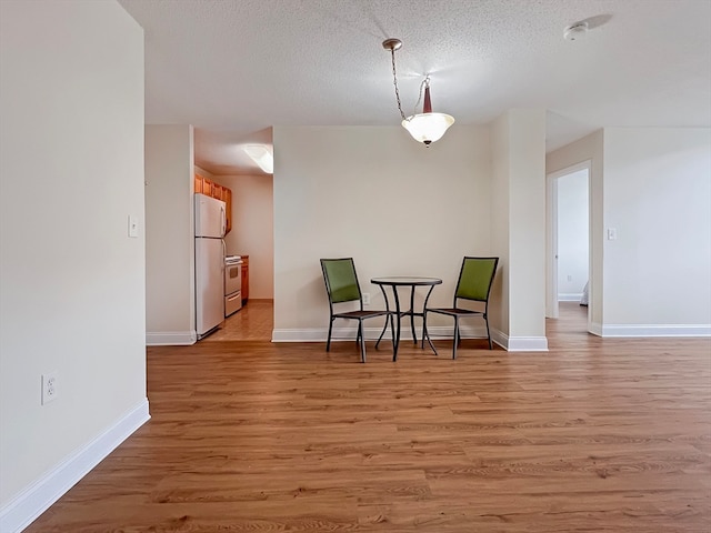 dining area featuring light wood-type flooring and a textured ceiling