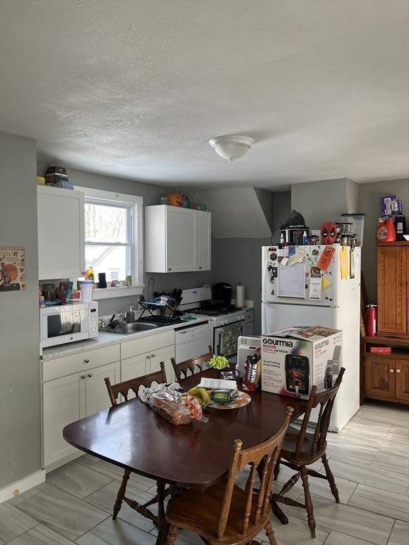 18 Dean St, Warren, MA 01083 - kitchen with white cabinets, a sink, a textured ceiling, and white appliances