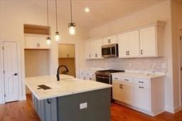 kitchen with tasteful backsplash, white cabinetry, stainless steel appliances, and light countertops