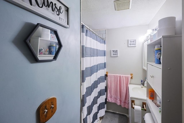 bathroom with vanity, a textured ceiling, and walk in shower