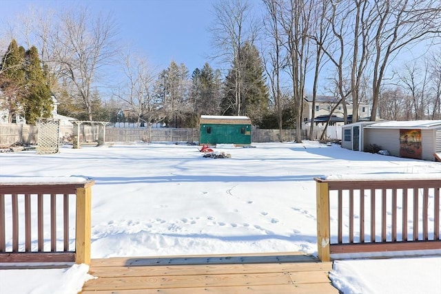 yard layered in snow featuring a deck and a storage unit