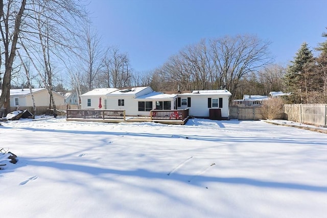 snow covered back of property with a wooden deck