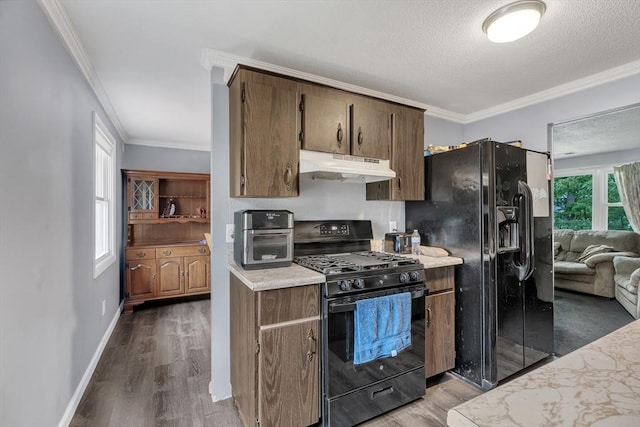 42 Charlotte Furnace Rd, Wareham, MA 02576 - kitchen with black appliances, under cabinet range hood, wood finished floors, light countertops, and crown molding