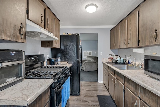 42 Charlotte Furnace Rd, Wareham, MA 02576 - kitchen featuring gas stove, under cabinet range hood, light wood finished floors, stainless steel microwave, and a textured ceiling