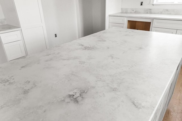 kitchen featuring light stone countertops and white cabinetry