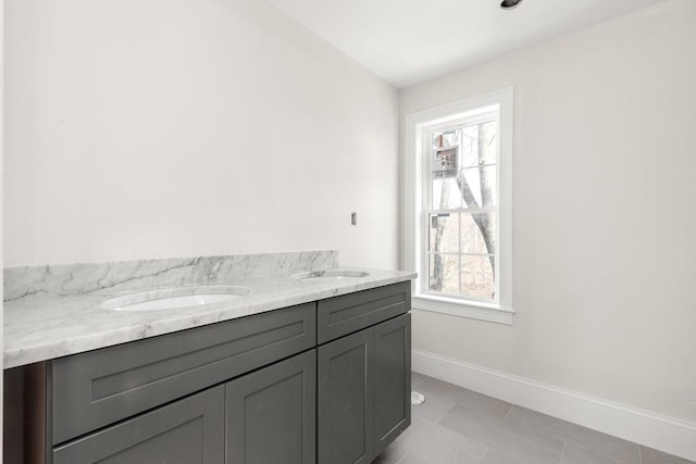 bathroom featuring baseboards, double vanity, plenty of natural light, and tile patterned floors