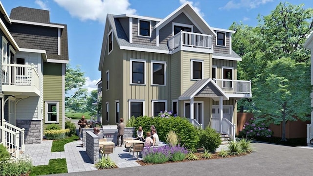 view of front of property featuring board and batten siding, roof with shingles, a balcony, and a patio area