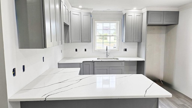 kitchen featuring sink, light hardwood / wood-style flooring, gray cabinetry, and ornamental molding