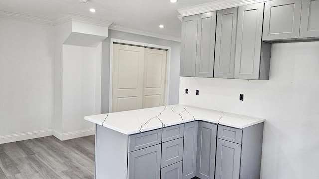 kitchen featuring crown molding, light hardwood / wood-style floors, kitchen peninsula, light stone counters, and gray cabinets