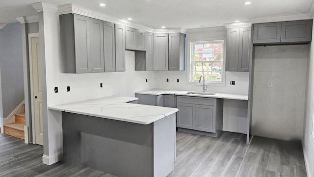 kitchen featuring sink, gray cabinets, kitchen peninsula, hardwood / wood-style flooring, and crown molding