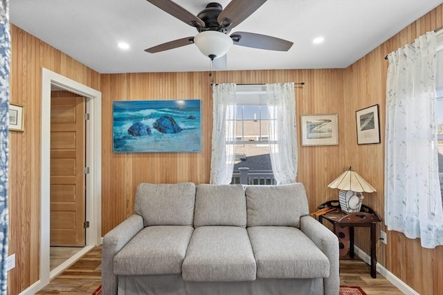 sitting room with ceiling fan, hardwood / wood-style flooring, and wooden walls