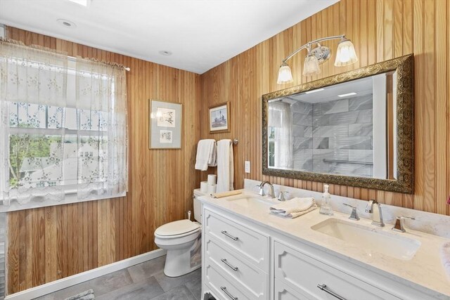 bathroom featuring toilet, wooden walls, plenty of natural light, and vanity