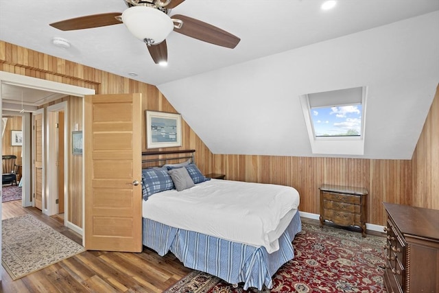 bedroom with ceiling fan, dark hardwood / wood-style flooring, and lofted ceiling with skylight