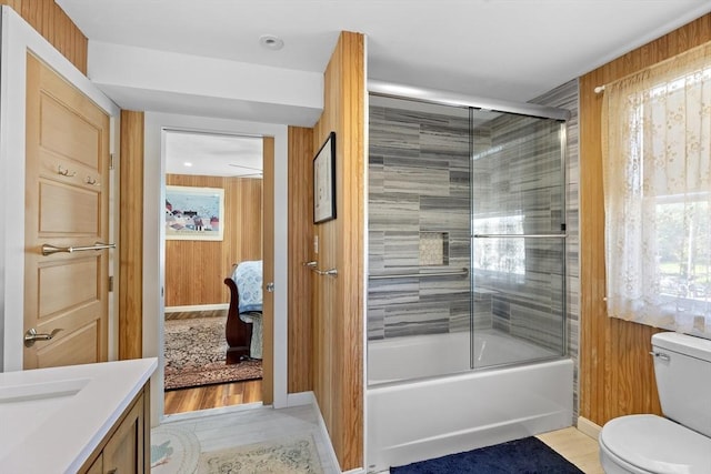 full bathroom with toilet, enclosed tub / shower combo, wood walls, and vanity