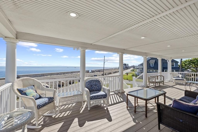 wooden terrace with a water view, an outdoor hangout area, and a view of the beach