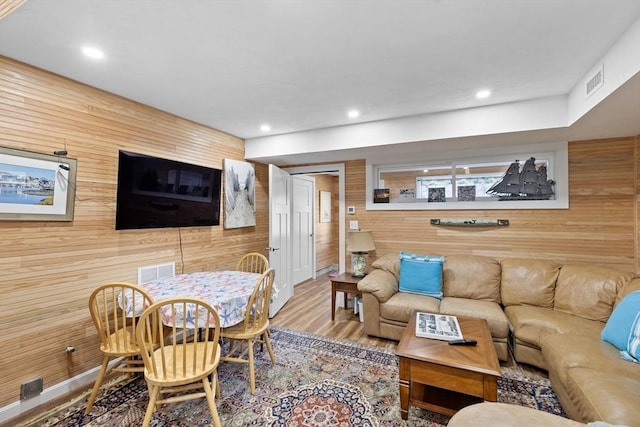 living room with hardwood / wood-style floors and wooden walls