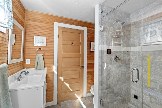 bathroom with vanity, toilet, an enclosed shower, and wooden walls