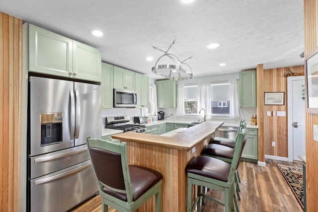 kitchen featuring a kitchen island, sink, appliances with stainless steel finishes, a breakfast bar area, and wood counters