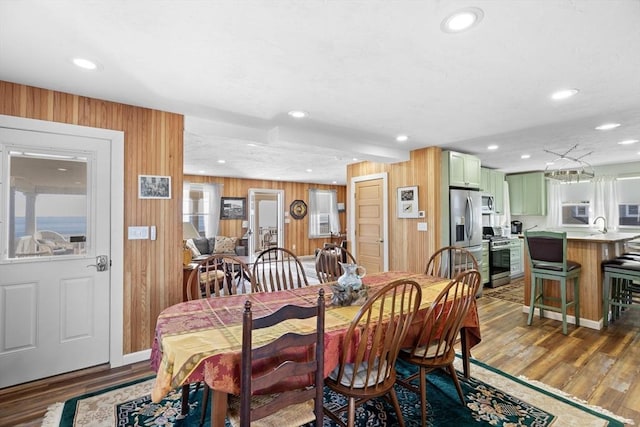 dining space with wood-type flooring, sink, and wood walls