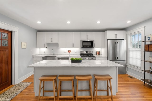 kitchen with appliances with stainless steel finishes, a center island, white cabinetry, sink, and a breakfast bar area