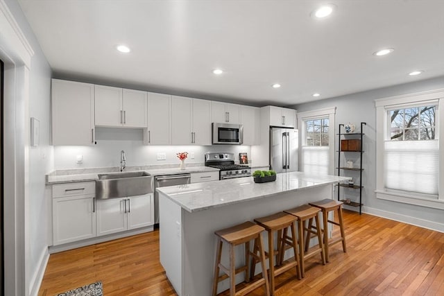 kitchen featuring a kitchen island, white cabinets, sink, and appliances with stainless steel finishes