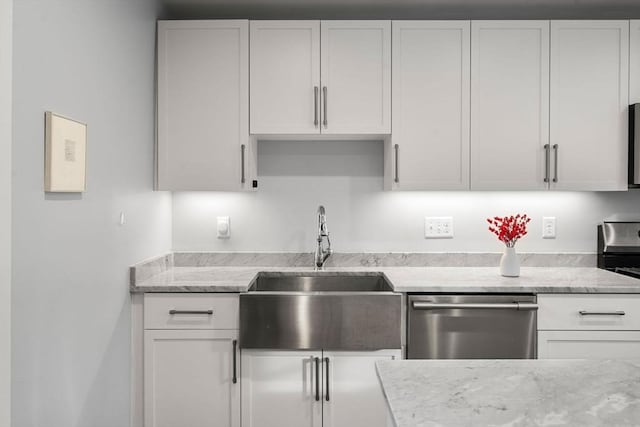 kitchen with light stone counters, sink, white cabinets, and dishwasher