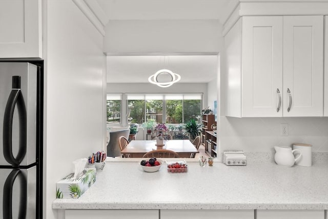 22 Chestnut Pl Unit 111, Brookline, MA 02445 - kitchen with freestanding refrigerator, white cabinetry, backsplash, and light stone countertops