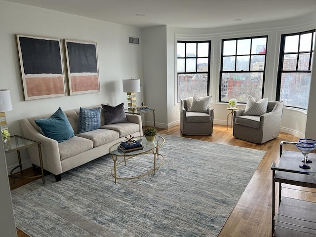 living room with visible vents, baseboards, and wood finished floors