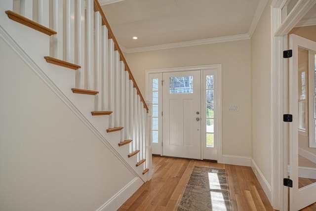 foyer entrance featuring a wealth of natural light, light hardwood / wood-style flooring, and crown molding