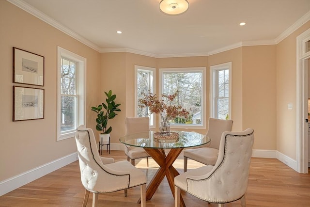 dining space featuring plenty of natural light, ornamental molding, and light hardwood / wood-style flooring