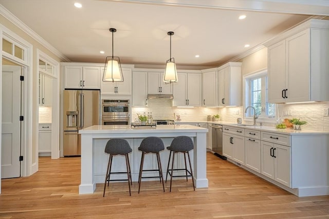 kitchen with white cabinets, a center island, crown molding, and appliances with stainless steel finishes