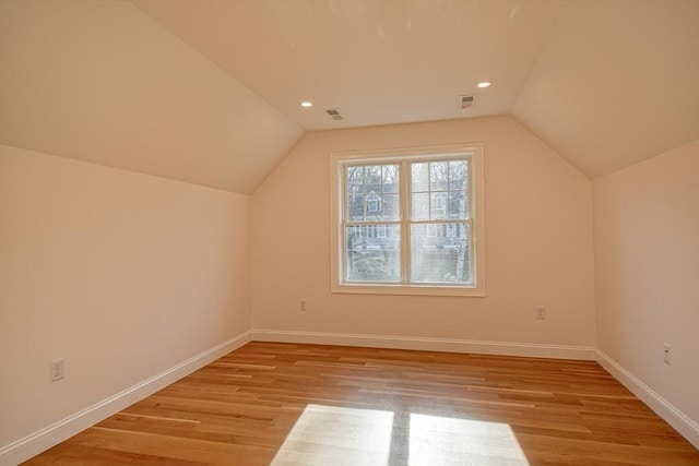 additional living space with vaulted ceiling and light hardwood / wood-style flooring